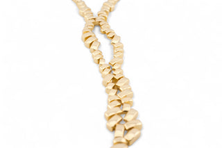 Gold lariat trendy necklace on a mannequin bust against a white background