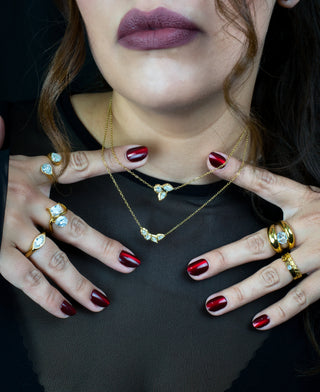 Close up of a woman wearing two layered gold plated pendant necklaces with zirconias