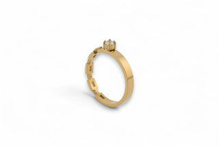 Gold band ring with a white gemstone on a white background