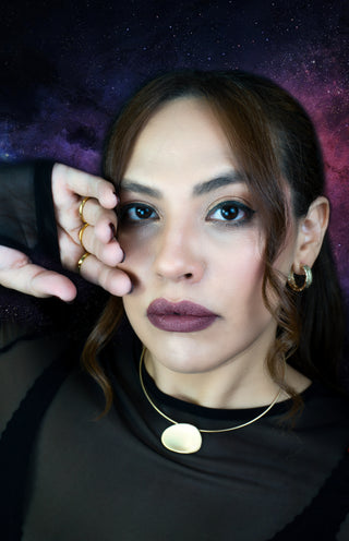 Woman with gold plated trendy jewelry set against a starry night sky background