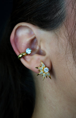 Close-up of an ear wearing gold plated and zirconia ear cuff and gold plated and zirconia star shaped earrings 