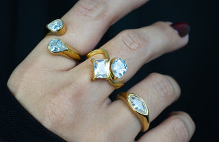 Gold rings with gemstones zirconias on a hand against a dark background