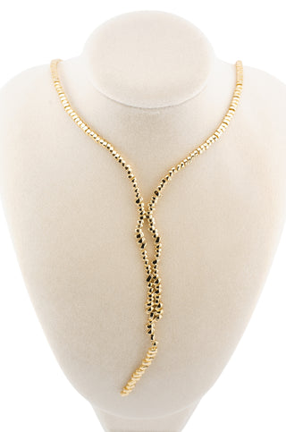 Gold lariat trendy necklace on a mannequin bust against a white background