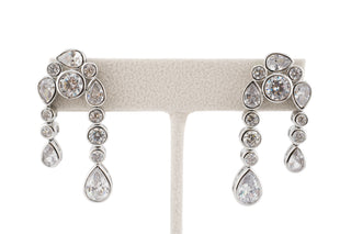 Pair of silver dangle earrings with clear gemstones zirconias on a white background