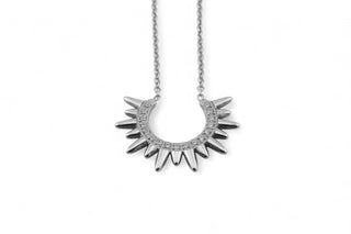 Silver necklace with a sunburst design on a white background