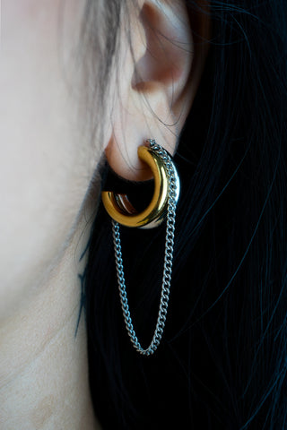Close-up of an ear with a gold-plated stainless steel hoop earring and chain detail.