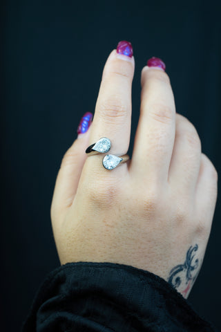 Hand wearing silver stainless steel ring with two zirconias with a dark background