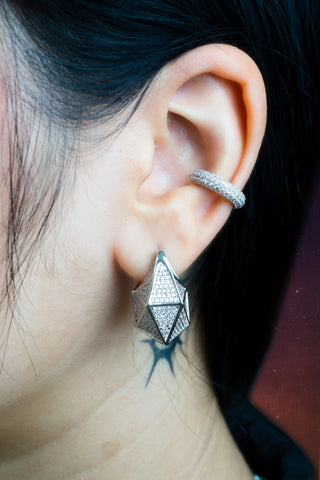 Close-up of an ear wearing a zirconia rhodium plated silver color huggie earring and cuff.