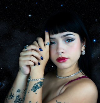 Woman wearing silver fine jewelry with zirconias against a starry night sky background